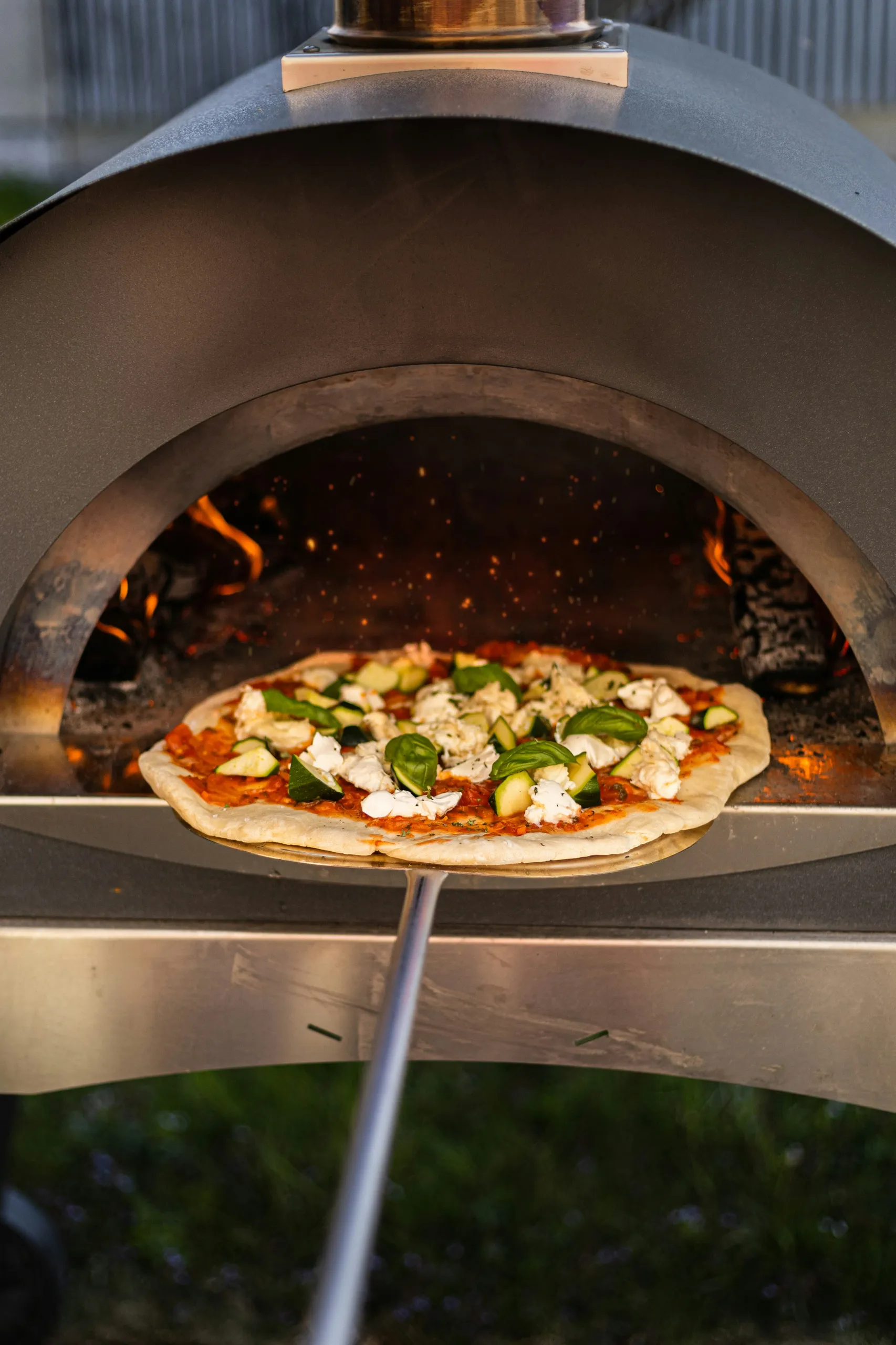 Pizza con calabacín y mozzarella saliendo del horno caliente