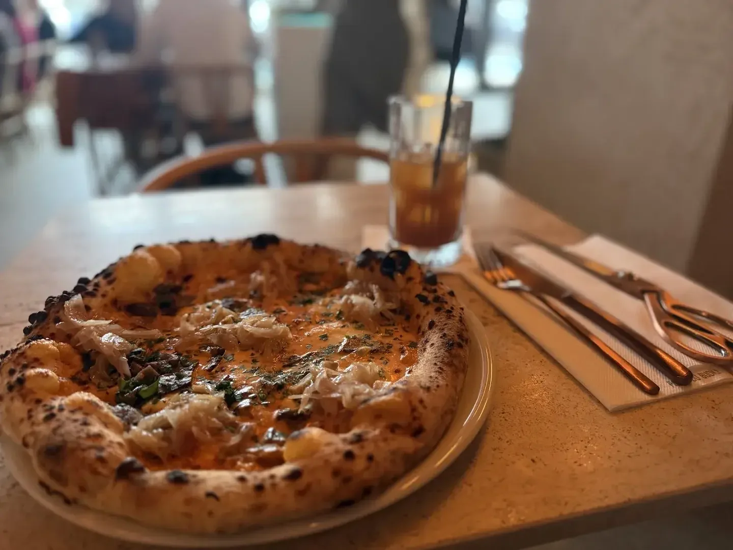 Pizza en tabla de madera con mozzarella y hierbas, copa de vino al lado