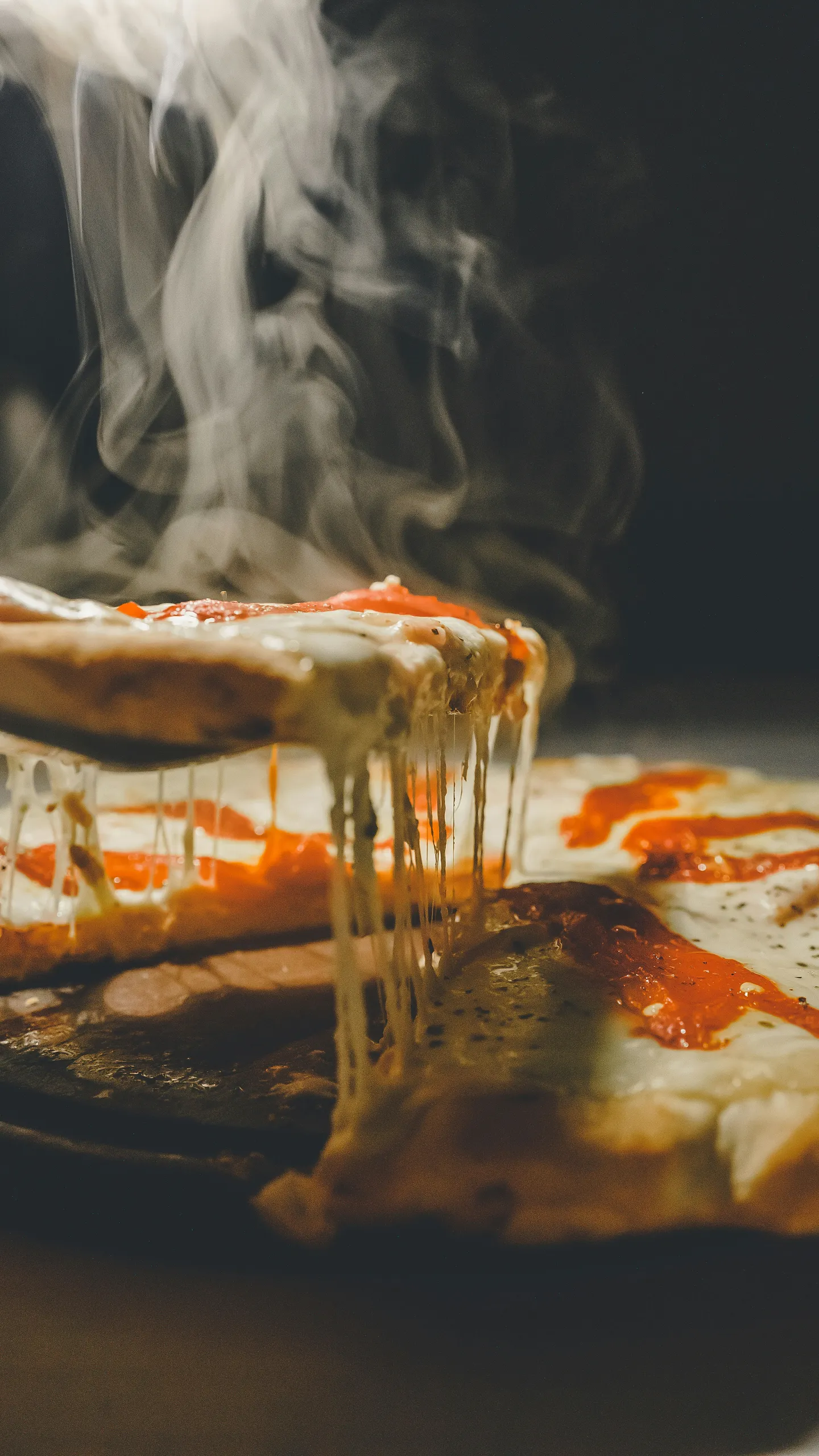 Pizza caliente con queso fundido y vapor elevándose sobre la porción