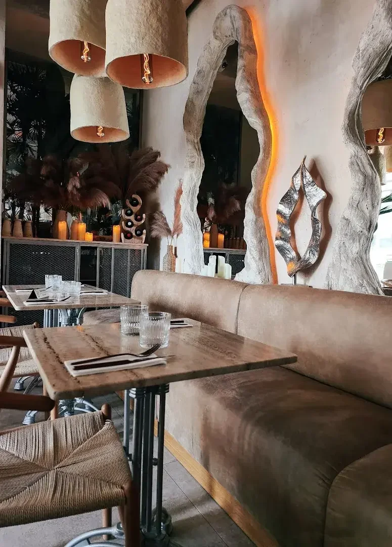 Sala del restaurante: asientos blancos, mesas de mármol, luces cálidas
